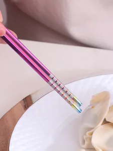 Detailopname van hand met paarse roestvrijstalen stokjes die een dumpling oppakken