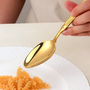 Cuillère dorée en acier inoxydable avec rayures sur des pâtes dans une assiette blanche