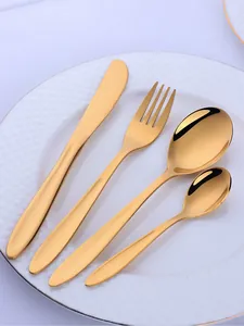 Macro shot of 4-piece gold stainless steel cutlery set on a white round ceramic plate