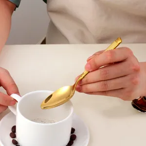 Gros plan d'une cuillère à café en acier inoxydable doré avec manche à rayures élégant