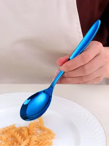 Close-up of a blue titanium-plated stainless steel spoon held over a white pasta plate