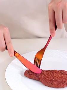 Macro detail of rainbow titanium stainless steel knife cutting a steak on a plate