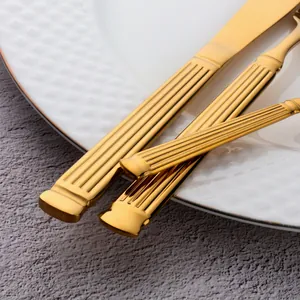 Ménagère en acier inoxydable doré avec manches striés sur une assiette en céramique