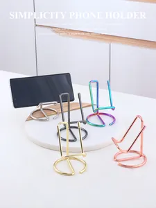 Five colorful metallic wire phone holders on marble tray with minimalist design