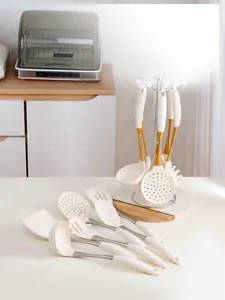 Detailed view of cream silicone kitchen utensils with gold accents on a modern counter