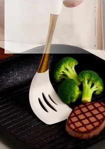 Macro shot of a heat-resistant white silicone spatula flipping steak in a skillet
