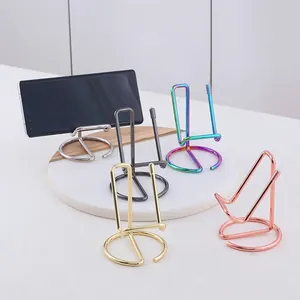 Minimalist metal phone stands in five metallic finishes shown from a 45-degree angle