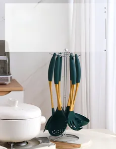 Detail of dark green silicone kitchen utensils with gold handles and metal storage rack