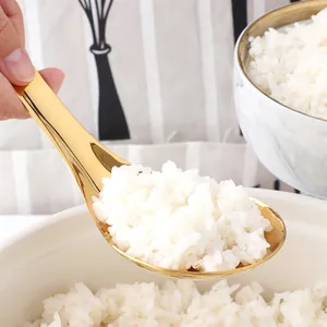 Macro shot of a golden stainless steel serving spoon scooping white rice from a bowl