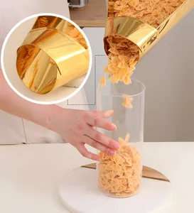 Golden stainless steel food funnel pouring farfalle pasta into a glass storage jar