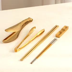 Détail d'un ensemble de couverts en acier inoxydable doré avec pinces et baguettes
