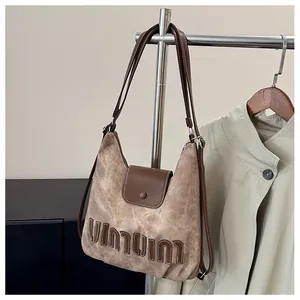 Nahaufnahme der braunen Vintage-Schultertasche aus Canvas mit geprägtem Markenschriftzug