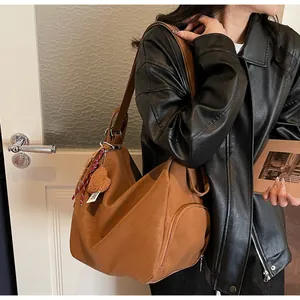 Braune Wildleder-Hobo-Tasche mit flauschigem Herzanhänger im Retro-Pendler-Stil am Modell