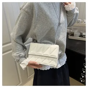 Detail of white quilted faux leather crossbody bag with elegant silver metal chain strap