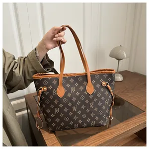 Detail of printed monogram tote bag with brown leather handles and side drawstring