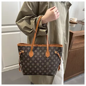 Detail of vintage brown monogram tote bag with leather handles and gold metal accents