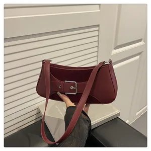 Detalle del bolso baguette burdeos con hebilla plateada y textura efecto cuero