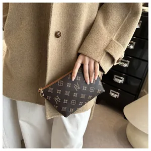 Close-up of small dark brown tote pouch with vintage floral pattern and gold zipper detail