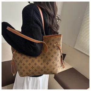 Side view of a vintage brown monogram tote bag styled with a black knitted sweater