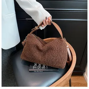 Detailed macro view of dark brown plush fabric texture and brown leather strap of the handbag