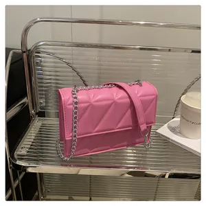 Close-up of bright pink quilted crossbody bag with silver chain and leather strap