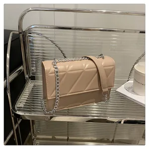 Macro view of beige quilted handbag with geometric triangle pattern and silver chain strap