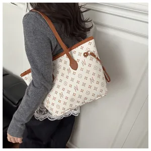 Detail of printed tote bag featuring brown leather trim and side drawstring toggle