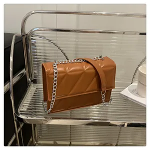 Close-up of brown geometric quilted crossbody bag with silver metal chain strap