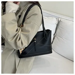 Detail of black leather tote bag with white contrast stitching and printed silk scarf