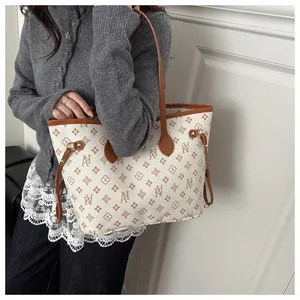 Detailed close-up of NY monogram pattern on cream tote bag with brown leather trim