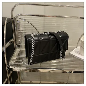 Detailed macro view of geometric quilted pattern and silver chain strap on black crossbody bag