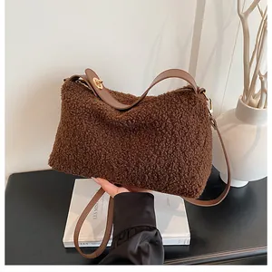 Detail of plush brown hobo bag with leather straps and golden metal buckle hardware
