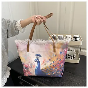 Detail of artistic peacock print tote bag with frayed edges and brown leather handles