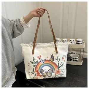 Detail of canvas tote bag with butterfly prints and white tassel edges with leather straps