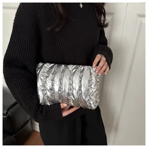 Detailaufnahme der silbernen gesteppten Clutch mit vertikaler Textur und Metallic-Finish