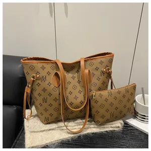 Detailed set of large brown monogram tote bag and matching zippered clutch on wooden table