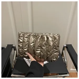 Detailed view of quilted metallic champagne envelope clutch with pleated texture