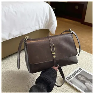Detail of vintage dark brown PU leather handbag with golden metal buckle and fine texture