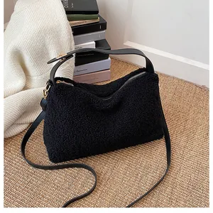 Detail of black teddy plush handbag featuring smooth faux leather straps and gold hardware