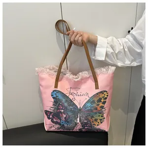 Detail of pink canvas tote with butterfly print, fringe edges and brown leather handles