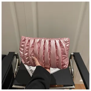 Close-up of a pink quilted envelope clutch bag with metallic satin finish and wavy stitching