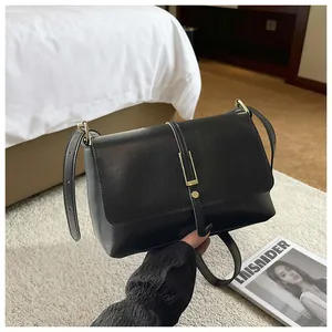 Detail of black faux leather handbag showing golden metal lock and adjustable shoulder strap