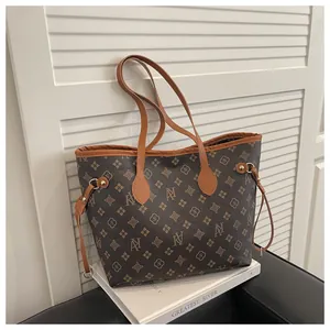 Detailed view of monogram print tote bag with brown leather handles and gold hardware
