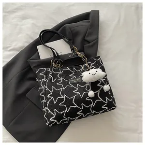 Top view of black tote bag with star embroidery, gold chain, and cloud charm detail