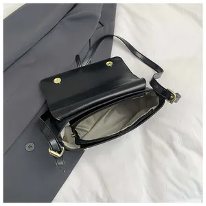 Detail of black crossbody bag interior showing light lining and central zipper divider