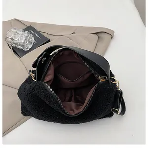 Close-up of black plush handbag interior showing brown lining and golden zipper