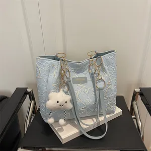 Light blue star-quilted tote bag with gold chain handles and cloud charm accessory