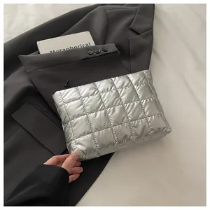 Détail de pochette matelassée argentée avec fermeture éclair sur une veste grise