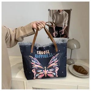 Close-up of canvas tote bag with butterfly print, fringe detail and leather straps