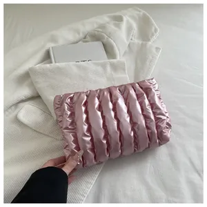 Detail der pinkfarbenen gesteppten Clutch-Tasche mit vertikalen Falten und Glanz